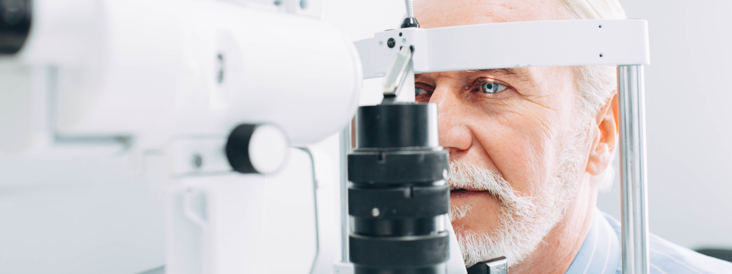 Älterer Mann sitzt vor Spaltlampe.